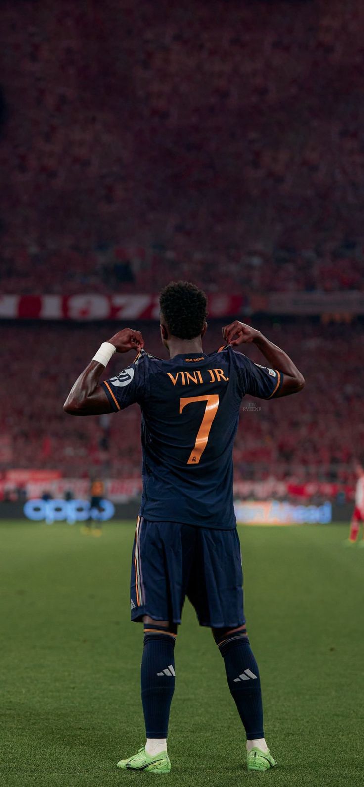 a man standing on top of a soccer field holding his hands behind his back as if he is ready to kick the ball