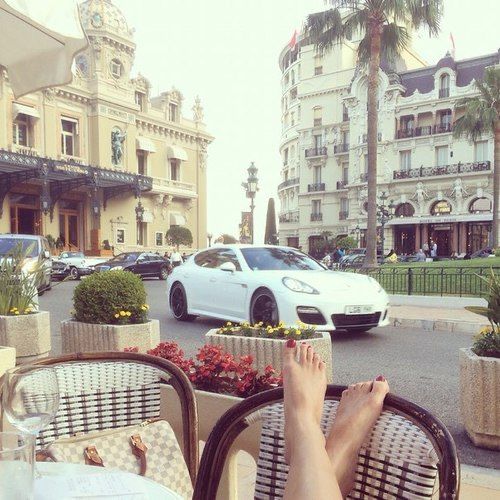 a person's feet resting on a table in front of a white car