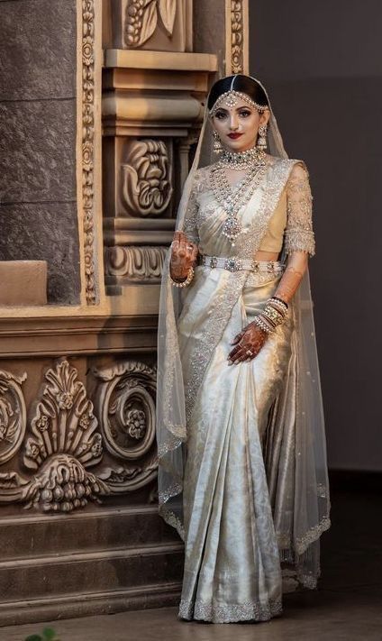 a woman wearing a white and gold sari