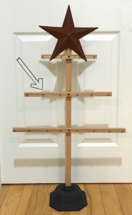 a wooden christmas tree with a star on top in front of a white door and wood floor