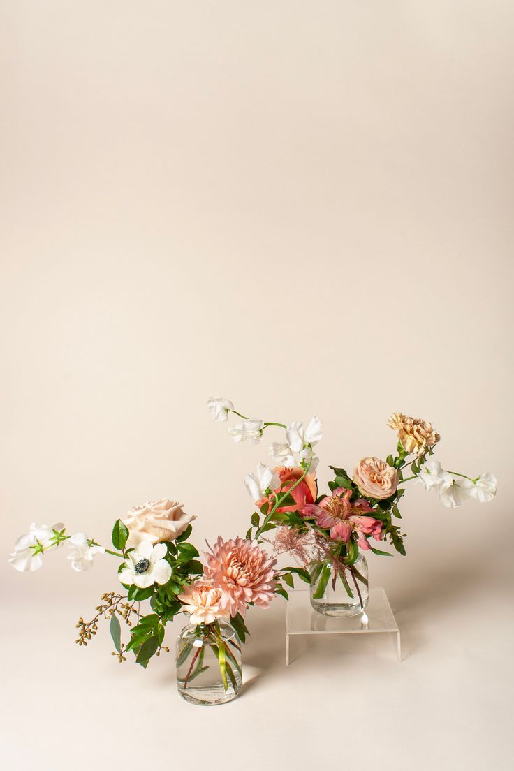 two vases with flowers in them on a table