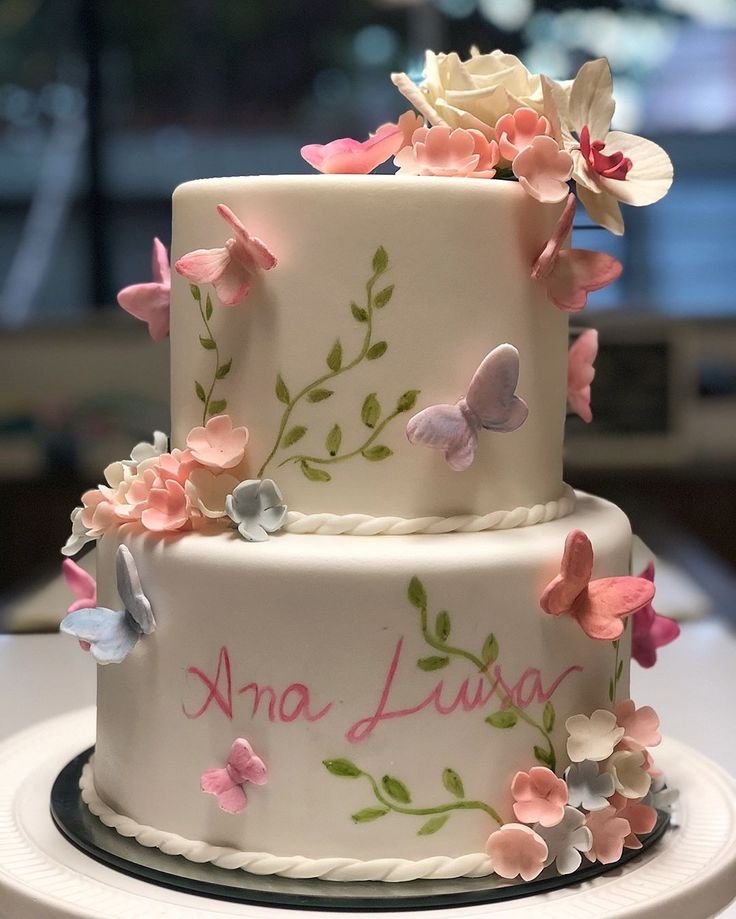 a three tiered cake decorated with flowers and butterflies