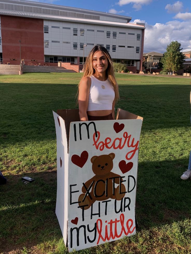 a woman standing next to a sign that says i'm very excited at my little teddy bear