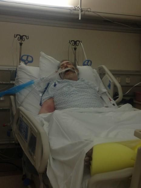 a man laying in a hospital bed with an oxygen tube attached to his arm and head