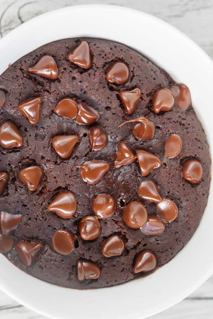 a white bowl filled with chocolate cake on top of a wooden table