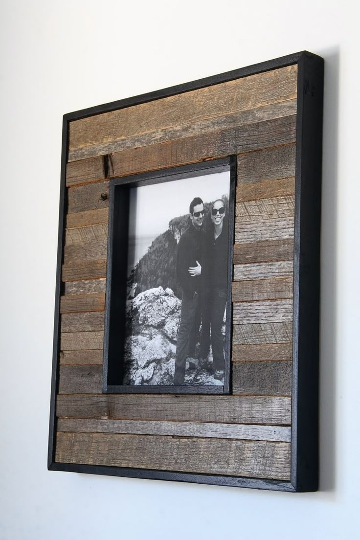 an old photo frame with two men standing next to each other in front of a white wall