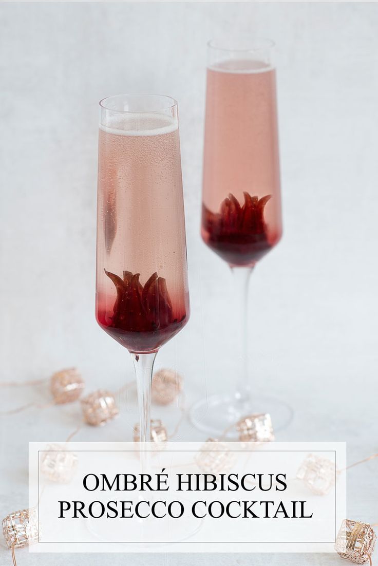 two wine glasses filled with pink liquid and garnished with rose petals, sitting next to each other