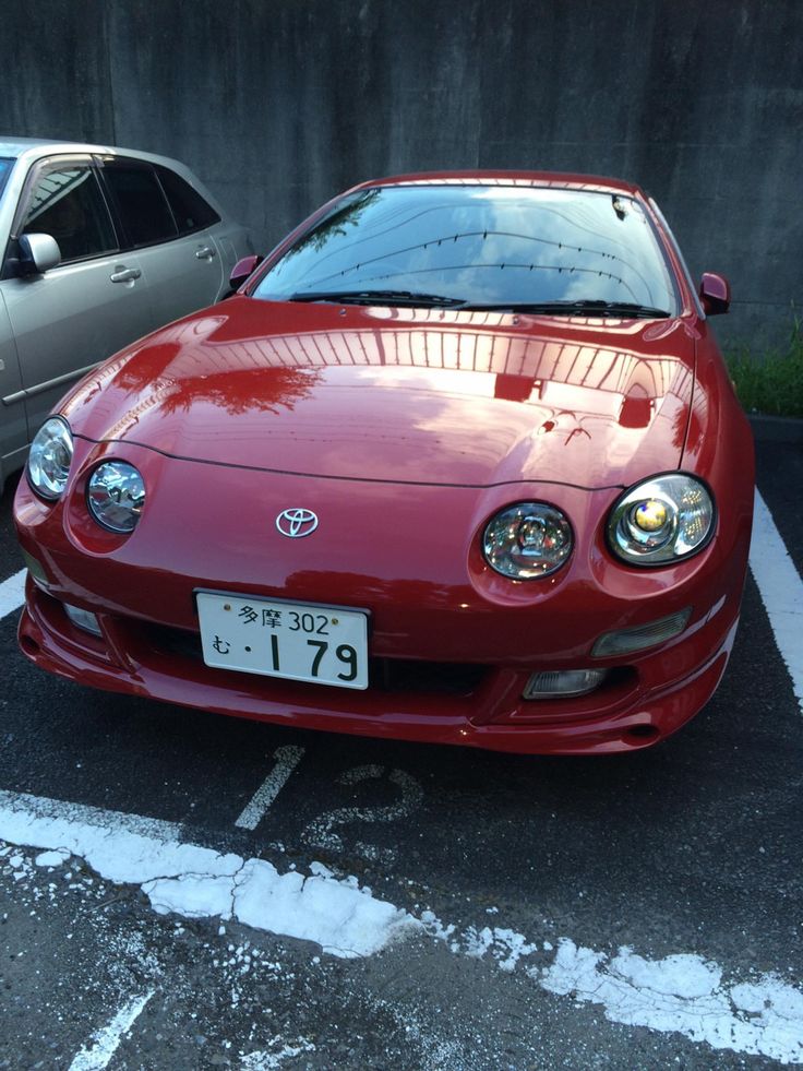 a red car parked in a parking lot next to another silver car on the street