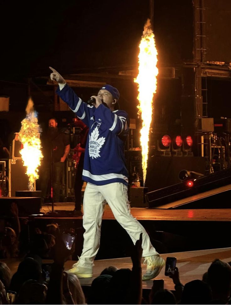 a man standing on top of a stage in front of a firework display at night