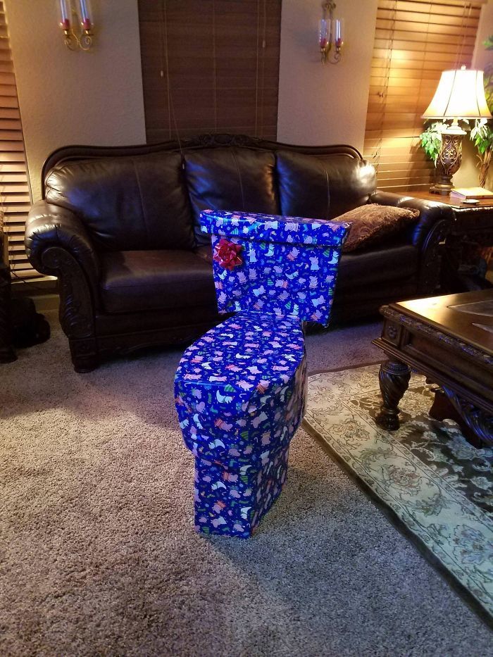 a living room filled with furniture and a large blue present box on the floor next to a coffee table