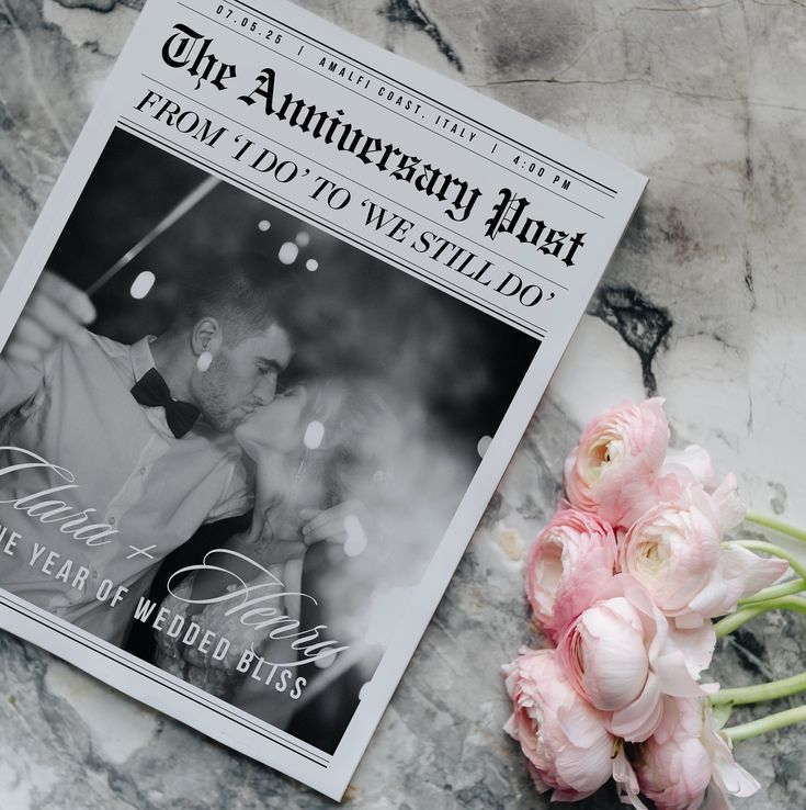 a wedding program and flowers on a marble counter top with the anniversary flatt magazine next to it