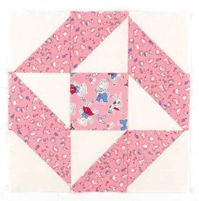 a pink and white patchwork quilt block with hearts on the bottom, along with an arrow in the center