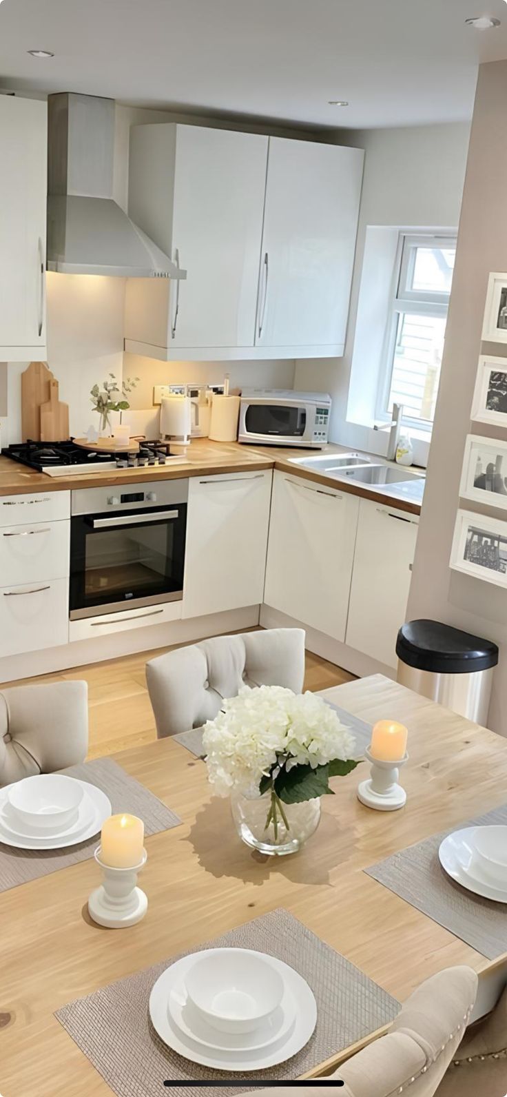 a dining table with place settings and candles on it in a modern style home kitchen