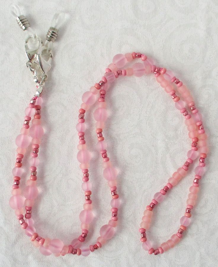 Keep your reading glasses nearby - use this light pink beaded eyeglass chain! 26" in length, made with glass beads, beading cord, metal lobster clasps, and adjustable rubber holders. Lobster clasps make it easy to change the rubber holders, and an extra pair of holders included with every purchase. This pretty light pink beaded eyeglass chain will arrive in a gift box, ready to give as a present or to keep and store. Back to Beaded Eyeglass Chains Cheap Pink Glasses Chains As Gift, Beaded Eyeglass Chain, Handmade Eyewear, Eyeglass Chains, Beading Cord, Eyeglass Chain, Pretty Lights, Eyewear Accessories, Reading Glasses