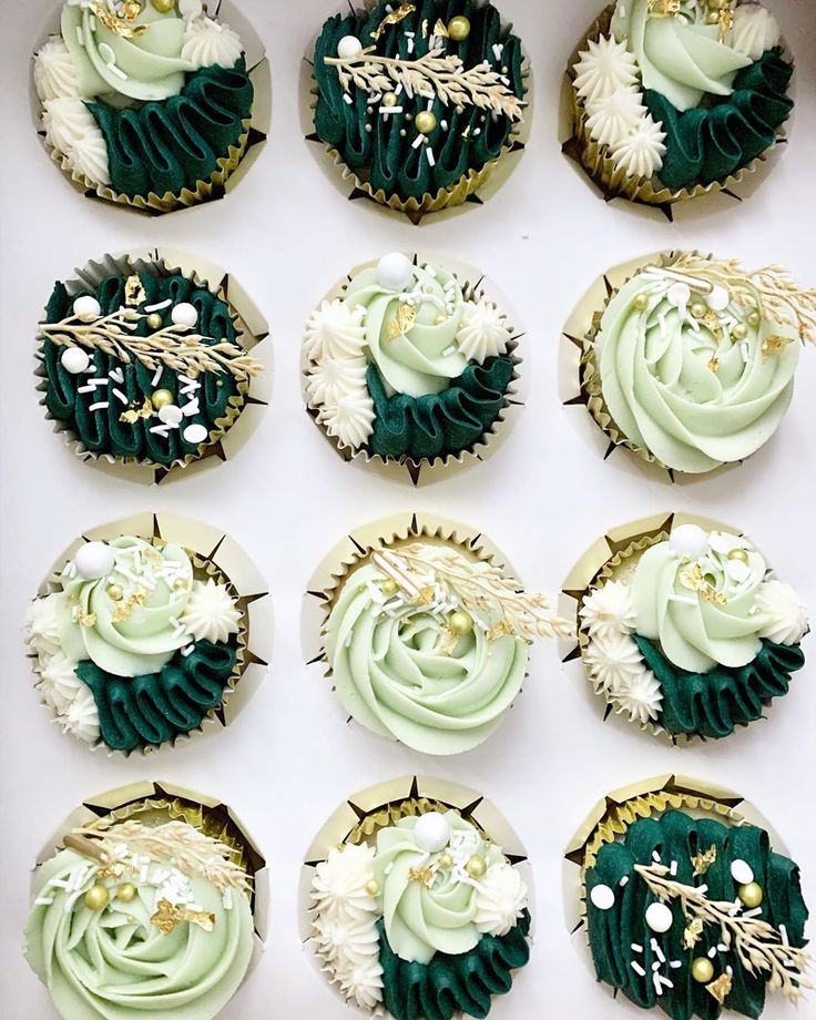 twelve cupcakes decorated in green and white frosting with gold decorations on top