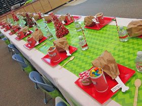 a table set up with red and green placemats, candy buckets, water bottles, and napkins