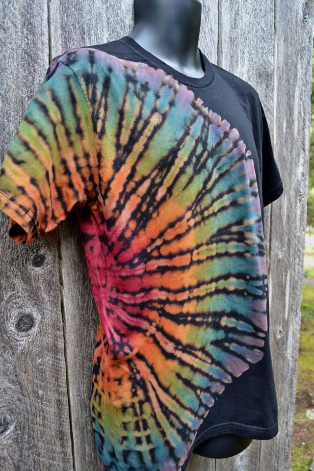 a tie - dyed shirt hanging on a wooden fence