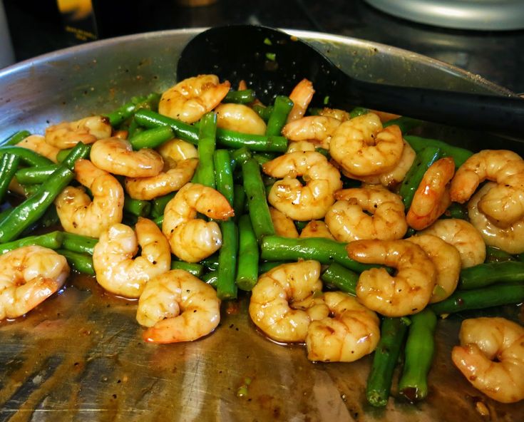 shrimp and asparagus are being cooked in a wok on the stove top