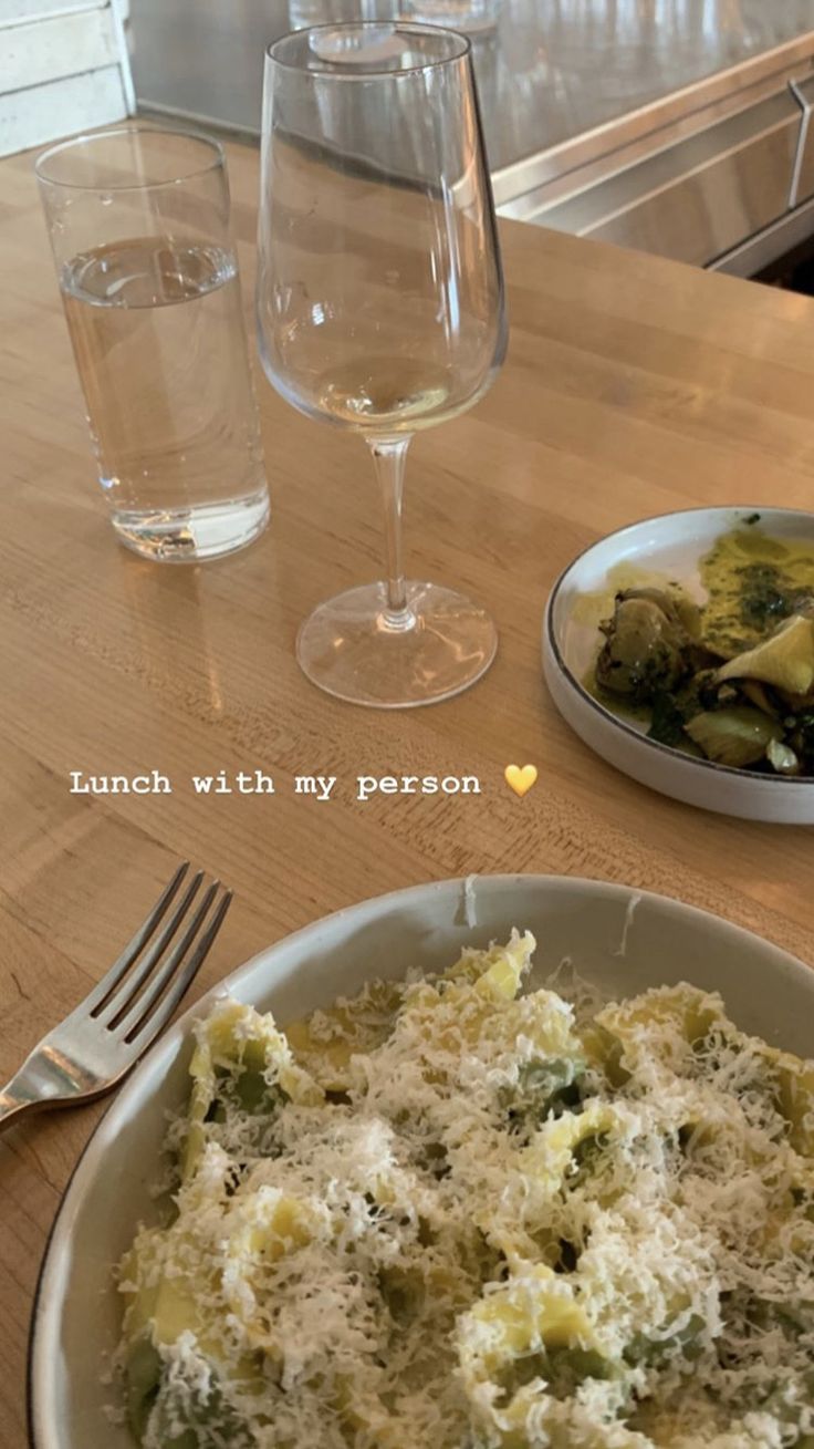 a plate of food with cheese and broccoli on it next to a glass of wine