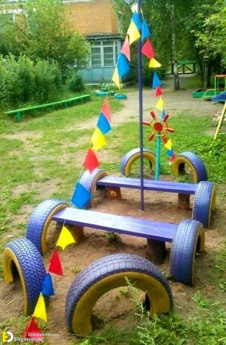 an upside down bench made out of old tires and colorful umbrellas on the ground