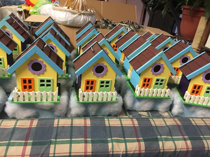 five birdhouses are lined up on a plaid tablecloth in the shape of houses