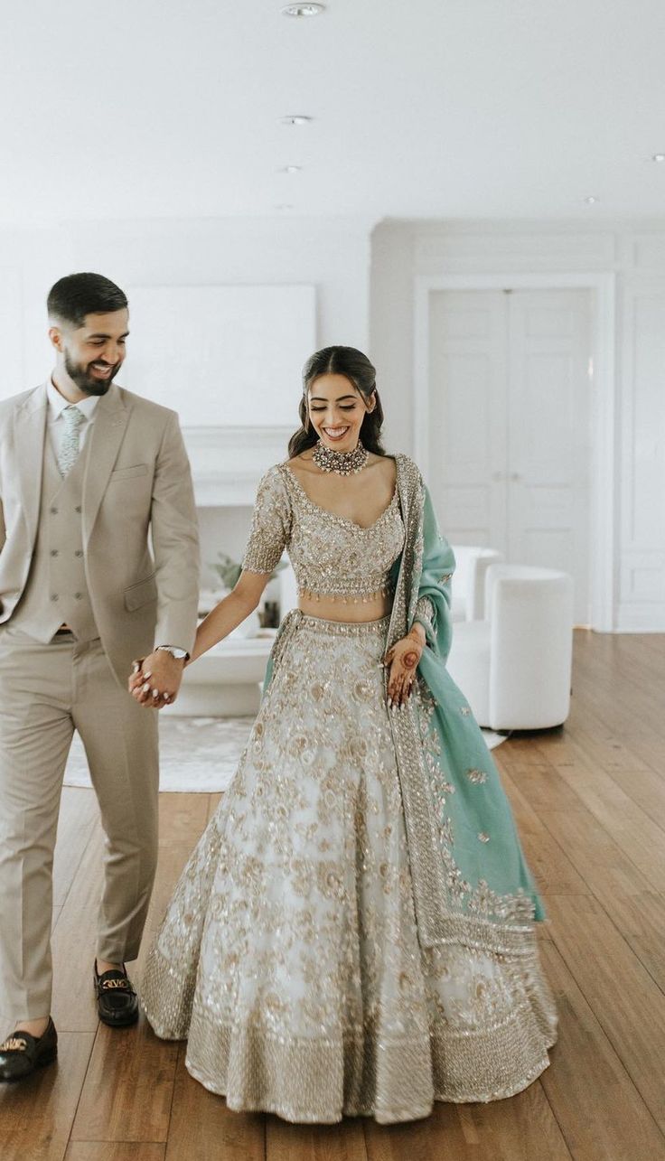 a bride and groom holding hands while walking through the room