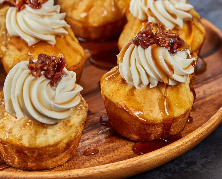 some cupcakes on a wooden plate with icing and toppings in them