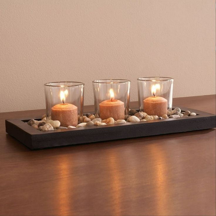 three candles are lit on a tray with rocks