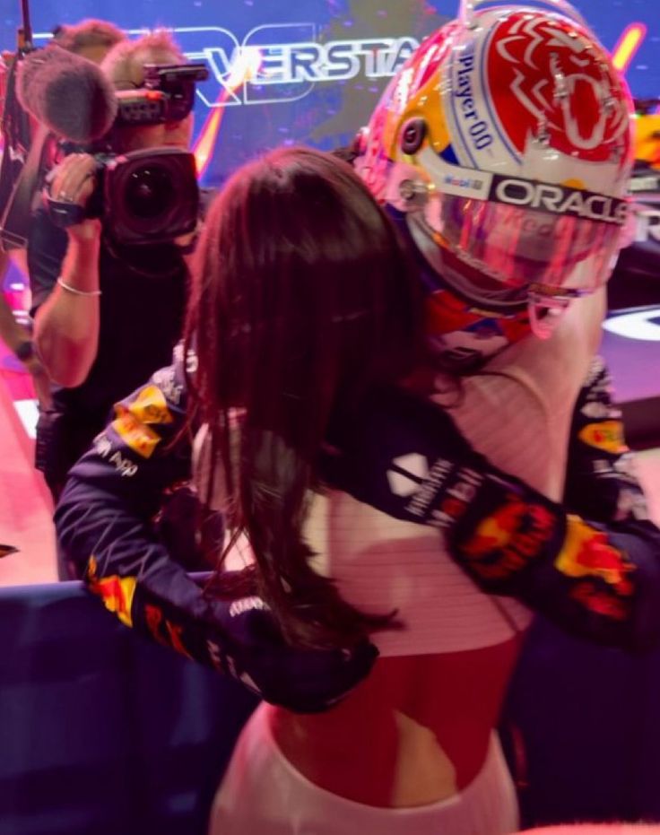 a woman wearing a red bull racing suit and helmet