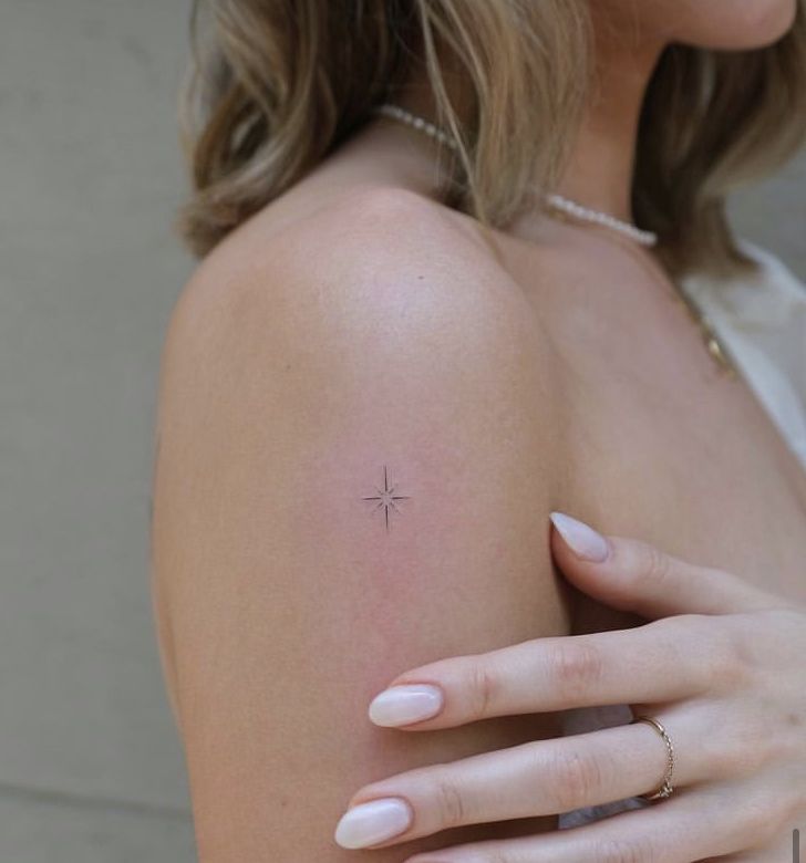 a woman's arm with a small cross tattoo on the left side of her arm