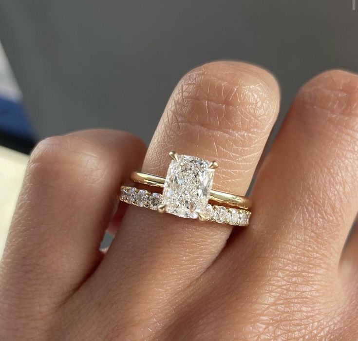 a woman's hand with a diamond ring on top of her finger and the engagement band