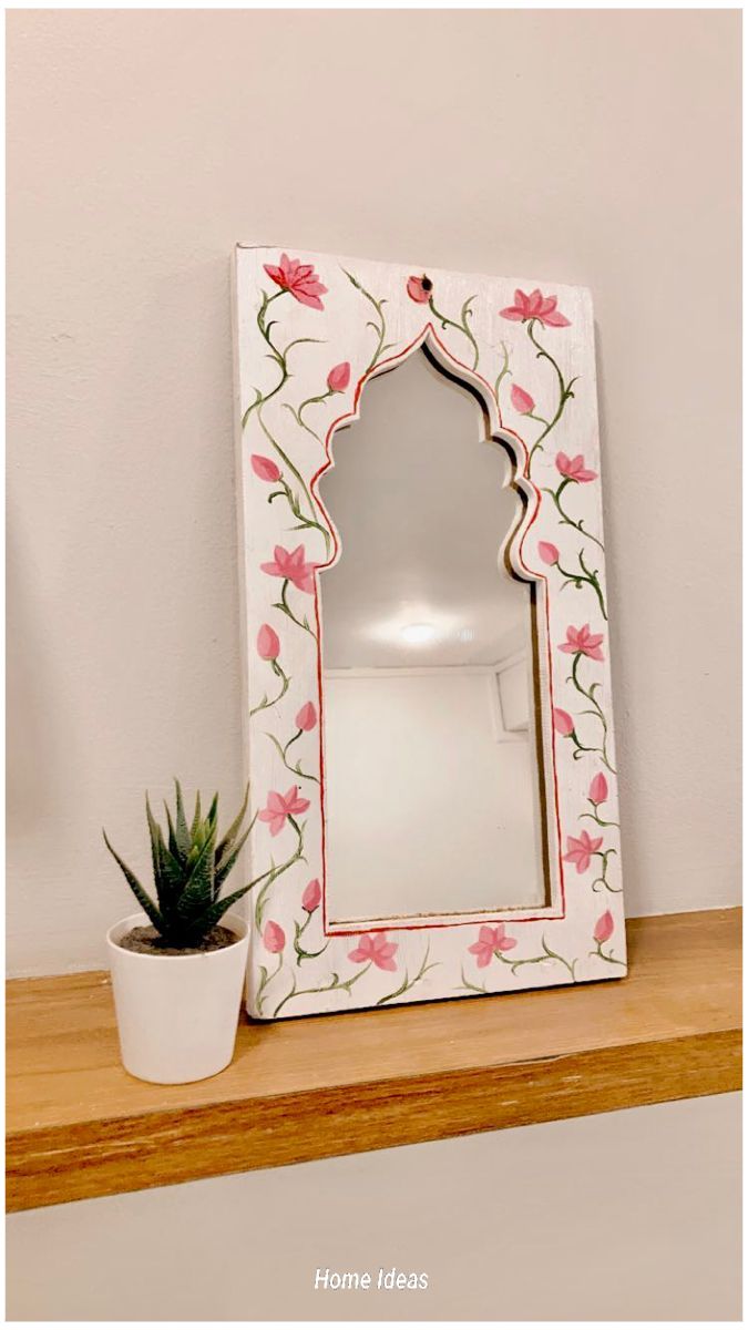 a white mirror sitting on top of a wooden shelf next to a potted plant