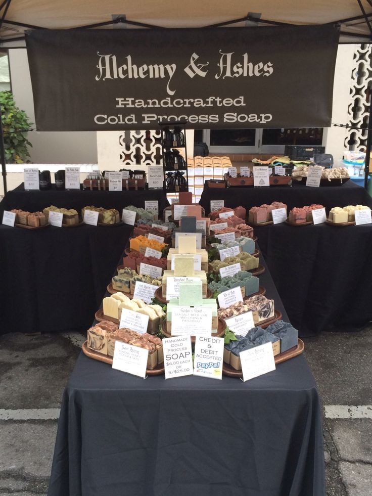 an outdoor market with many different types of soaps on display under a black awning