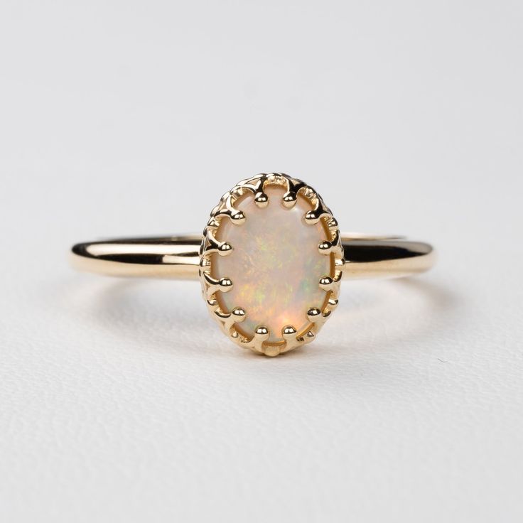 This antique style crown ring comes with a gorgeous Australian oval opal. If you want a different stone or want to add accent diamonds contact us for a quote. Details: - Default stone size is 7x5mm Australian Opal in oval shape. - Shiny finish by default. - Default width is 1.8mm at the bottom and 8.7x6.5mm at the top - Default thickness is 1.6mm at the bottom and 2mm at the top. - Contact us for quote if you want to customize this ring in any way. Thank you for shopping with Sevgi Jewelry! Classic Moonstone Opal Ring For Anniversary, Classic Opal Moonstone Anniversary Ring, Classic Cabochon Opal Ring, Oval Opal Halo Ring In 14k Gold, Exquisite Oval Opal Ring, Elegant Oval Cluster Ring With Cabochon, Elegant Oval Cabochon Cluster Ring, Classic 14k Gold Moonstone Ring Oval Cabochon, Heirloom 14k Gold Opal Ring Oval Cabochon