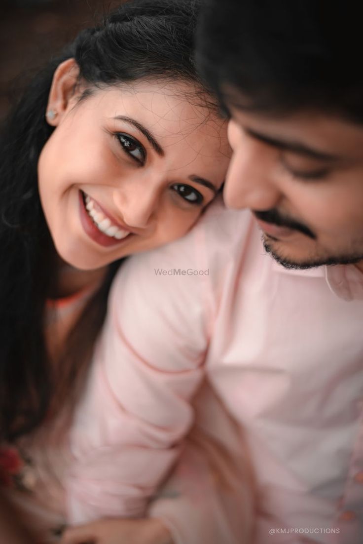 a man and woman smile at the camera while they are cuddling close to each other