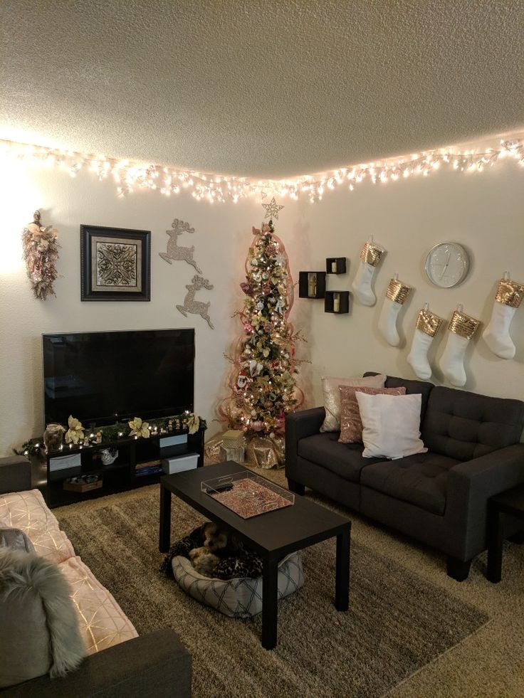 a living room filled with furniture and a christmas tree in front of a tv mounted on the wall