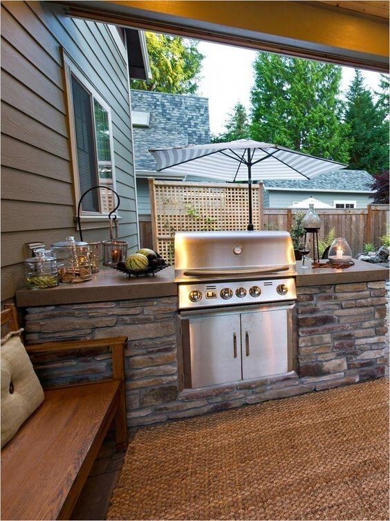 an outdoor kitchen with grill and seating area