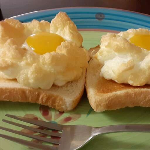 two pieces of bread with eggs on them and a fork sitting next to the plate