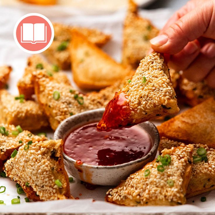 a person dipping sauce into some food on a plate