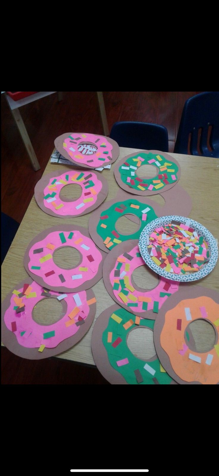 paper plates with donuts and sprinkles on them sitting on a table