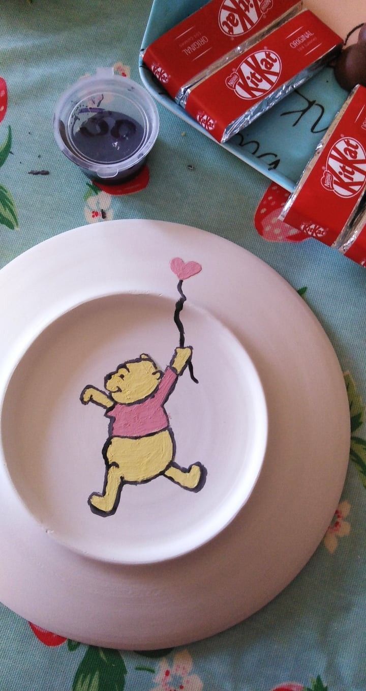 a winnie the pooh plate on a table next to some candy bar wrappers