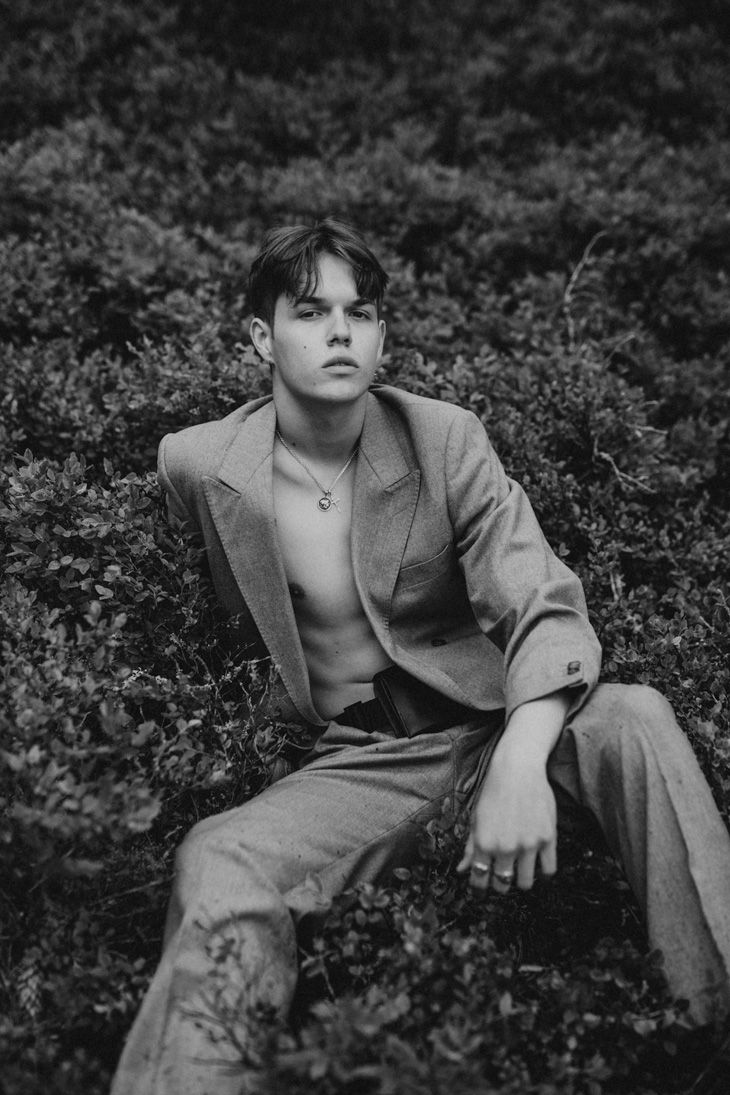 black and white photograph of a man sitting in the grass