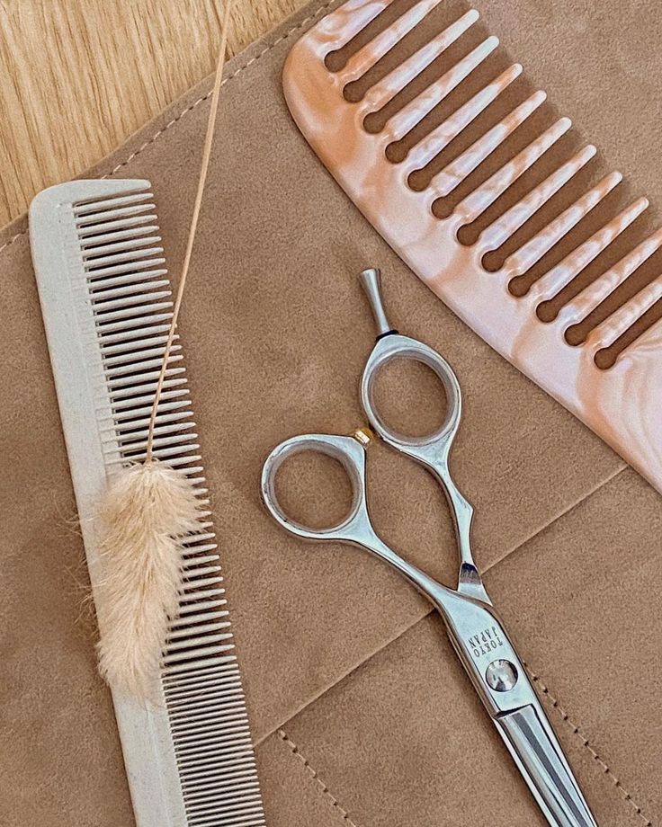 a pair of scissors sitting next to a comb on top of a piece of cloth