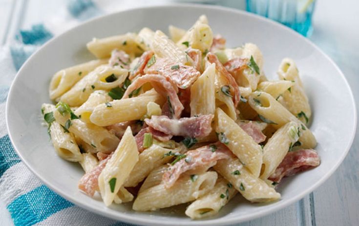 a white bowl filled with pasta and ham