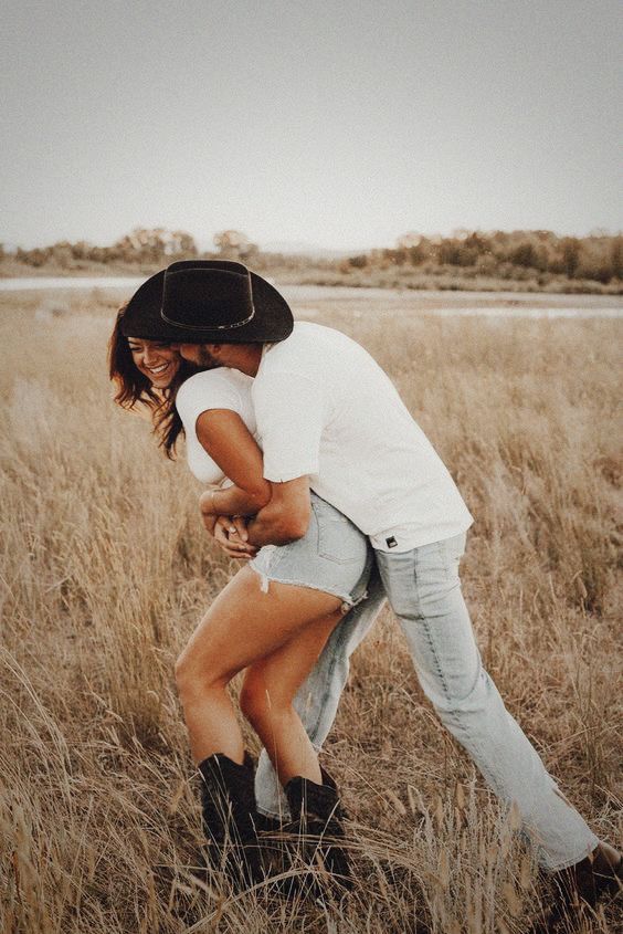 a man and woman are hugging in the middle of an open field with tall grass