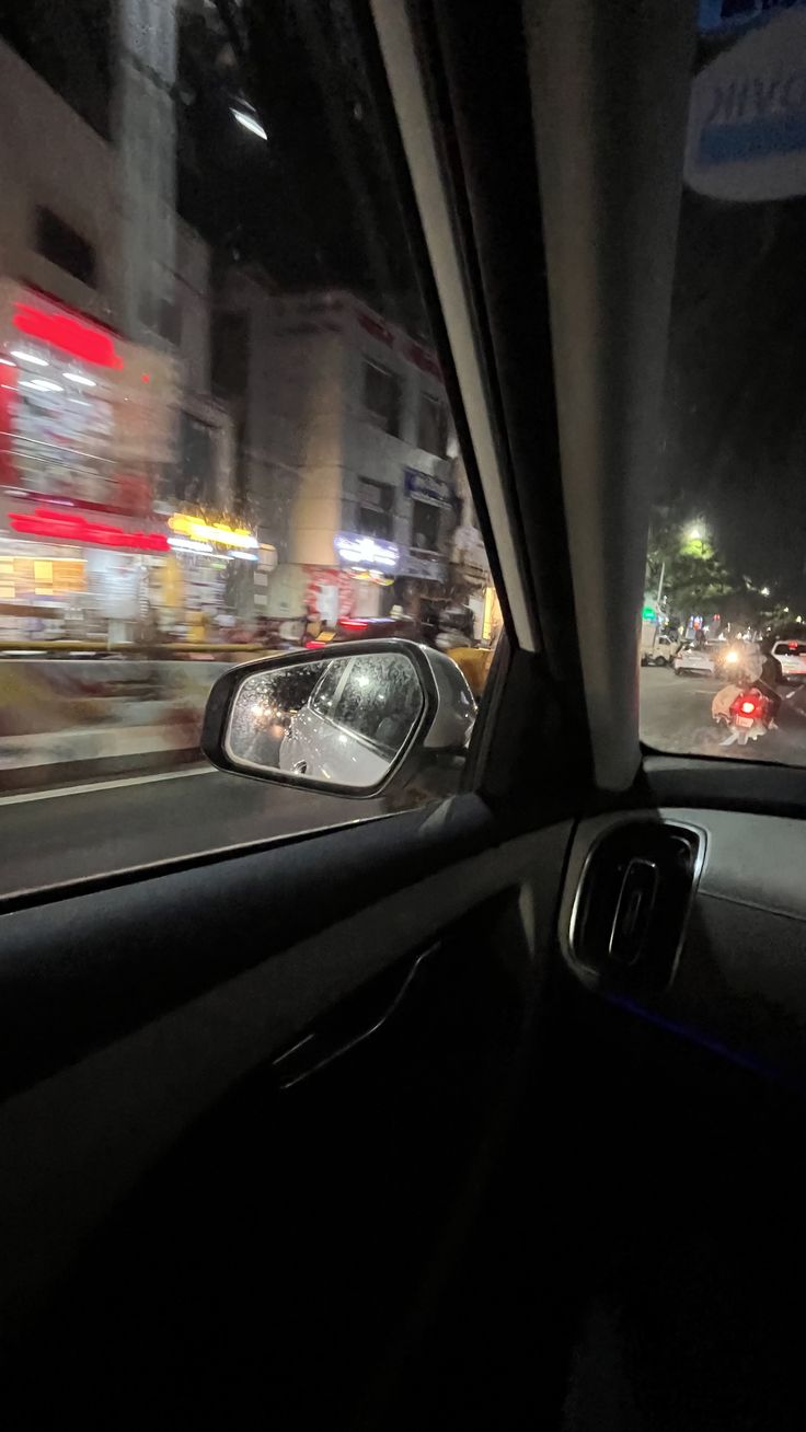 the view from inside a car driving down a street at night with blurry traffic