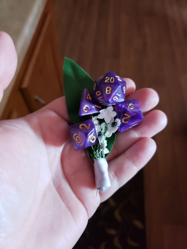 a hand holding a purple and white flower with numbers on it