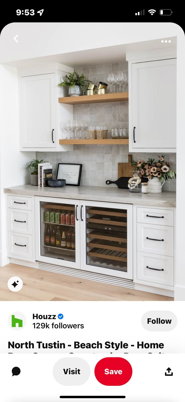 a white kitchen with lots of cabinets and wine glasses on the counter top in front of it