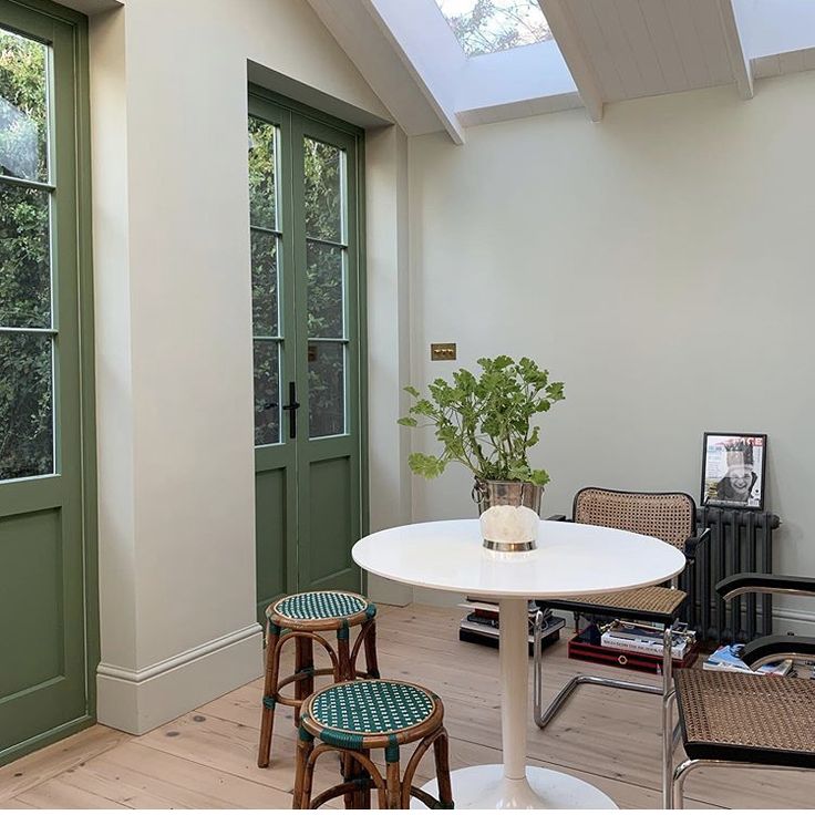 a white table and chairs in a room with green doors on the side walk way