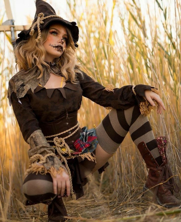 a woman dressed up as a witch sitting in the middle of a field with her legs crossed